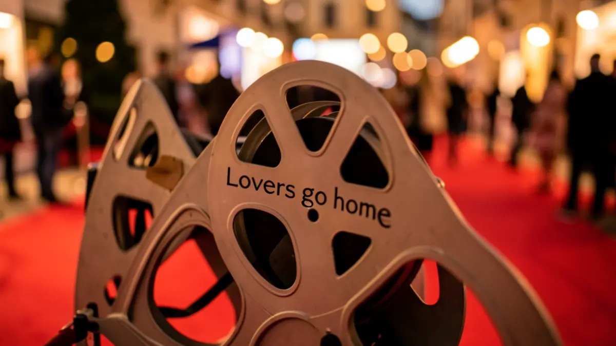 Image générique d'une bobine de film avec le titre 'Lovers go home' sur un tapis rouge de festival de cinéma.